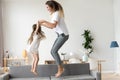 Happy mommy and kid daughter holding hands jumping on sofa Royalty Free Stock Photo