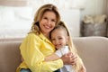 Happy Mommy And Little Daughter Embracing Smiling To Camera Indoor