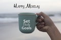 Happy Monday. Monday concept with business motivational text message on a coffee cup in hand - Set daily goals. Monday goal.