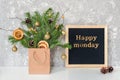 Happy Monday text on black letter board and festive bouquet of fir branches with christmas decor in craft package on table.