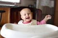 Happy 6 Month Old Baby Girl in Bib Eating at High Chair Royalty Free Stock Photo