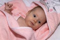 Happy 3 months old baby with a hooded pink towel lying on a bed Royalty Free Stock Photo