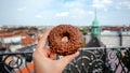 Happy morning with sweet breakfast in historical city. Donut in hand of person walking through streets of Copenhagen
