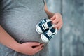 Happy mother in anticipation of the birth of her son. Pregnant woman holding baby booties sneakers on tummy background. Close-up Royalty Free Stock Photo