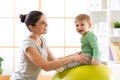 Happy mother with baby son doing gymnastics on the big fitness ball in the gym. Royalty Free Stock Photo