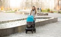 Happy mother with baby stroller walking on street near fountain Royalty Free Stock Photo