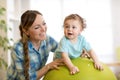 Happy mother and baby boy on fitness ball in nursery at home. Gimnastics for kids on fitball. Royalty Free Stock Photo