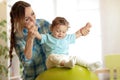 Happy mother and baby boy on fitness ball in nursery at home. Gimnastics for kids on fitball. Royalty Free Stock Photo