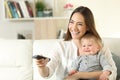 Happy mother and baby watching tv at home