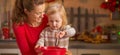 Happy mother and baby whisking dough in christmas kitchen