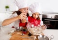 Happy mother baking with little daughter in apron and cook hat with flour dough at kitchen Royalty Free Stock Photo