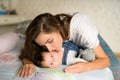 Happy mother in bed with her baby. Portrait of a beautiful loving mother playing first games with her baby in the bedroom Royalty Free Stock Photo