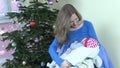 Happy mother breastfeed feed infant baby near Christmas tree