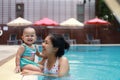 Happy mother and cheerful little baby girl enjoy playing together at outdoor swimming pool in long vacation. Family activity. Royalty Free Stock Photo