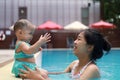 Happy mother and cheerful little baby girl enjoy playing together at outdoor swimming pool in long vacation. Family activity. Royalty Free Stock Photo