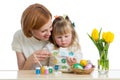 Happy mother and child daughter painting on Easter eggs Royalty Free Stock Photo