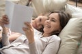 Happy mother and child daughter reading book laughing in bed Royalty Free Stock Photo