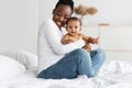 Black mom sitting on bed with her cute baby Royalty Free Stock Photo