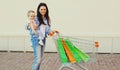Happy mother and child with shopping bags and trolley cart walking in a city Royalty Free Stock Photo