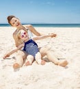 Happy mother and child in swimsuits at sandy beach playing Royalty Free Stock Photo