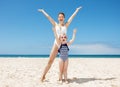 Happy mother and child in swimsuits at sandy beach rejoicing Royalty Free Stock Photo