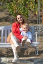 Happy mother and child swinging outdoor. Young mother with little kid son sitting on swing in summer park. Mothers day Royalty Free Stock Photo