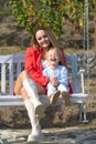 Happy mother and child swinging. Young mother with little kid son sitting on swing in summer park. Mothers day Royalty Free Stock Photo