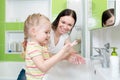 Happy mother and child washing hands with soap in