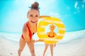 Happy mother and child with yellow inflatable lifebuoy on beach