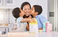 Happy, mother and children kissing cheek for love, baking and mothers day celebration in the kitchen at home. Mama smile