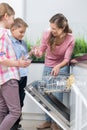 Happy mother and children placing glasses in dishwasher Royalty Free Stock Photo