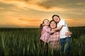 Happy mother and childs in green field at sunset