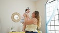 Happy mother confidently standing at home, holding her lovely baby daughter in arms, enjoying family love together in their indoor Royalty Free Stock Photo