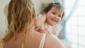 Happy mother confidently standing at home, holding her lovely baby daughter in arms, enjoying family love together in their indoor Royalty Free Stock Photo