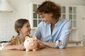 Happy mother and little girl holding piggy bank, saving money Royalty Free Stock Photo