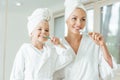 happy mother and daughter in bathrobes and towels brushing Royalty Free Stock Photo