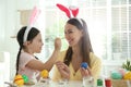 Happy mother and daughter with bunny ears headbands having fun while painting Easter eggs Royalty Free Stock Photo