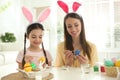 Happy mother and daughter with bunny ears headbands painting Easter eggs Royalty Free Stock Photo