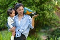 happy mother and daughter feeding blue-and-yellow macaw (Ara ararauna) bird on hand Royalty Free Stock Photo