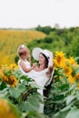 Happy mother with the daughter in the field with sunflowers. mom and baby girl having fun outdoors. family concept Royalty Free Stock Photo