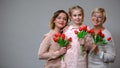 Happy mother, daughter and granny holding tulips grey background, spring holiday