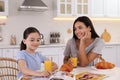 Happy mother and daughter having breakfast in kitchen. Single parenting