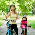 Happy mother and daughter having fun, riding a bicycle and showing thumbs up Royalty Free Stock Photo