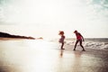 Happy mother and daughter having fun on tropical beach at sunset - Family playing next sea during summer vacation Royalty Free Stock Photo