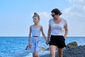 Happy mother and daughter kid walking together holding hands along sea beach Royalty Free Stock Photo