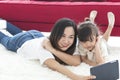 Happy mother and daughter playing together in bedroom taking a selfie. Mother and daughter on sofa at home smile making self-portr Royalty Free Stock Photo