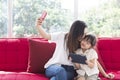 Happy mother and daughter playing together in bedroom taking a selfie. Royalty Free Stock Photo