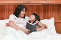 Happy mother and daughter reading book on bed Royalty Free Stock Photo