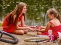 Happy mother with daughter rides bicycle and sitting on beach. Royalty Free Stock Photo