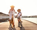 Happy mother and daughter riding bikes on pier